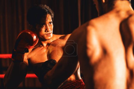 Foto de El boxeador asiático y caucásico Muay Thai desata su poder en un feroz combate de boxeo. Boxeador tailandés con un fuerte cuerpo muscular intercambiando golpes y golpes con destreza de combate implacable. Impulso - Imagen libre de derechos