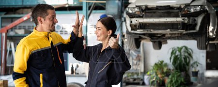 Photo for Two happy vehicle mechanic celebrate and high five after made successful car inspection or repair in automotive service car workshop. Technician team enjoy accomplishment together. Panorama Oxus - Royalty Free Image