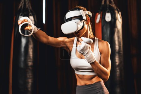 Photo for Female boxer training with VR or virtual reality, wearing VR headset with immersive boxing training technique using controller to enhance her skill in boxing simulator. Impetus - Royalty Free Image