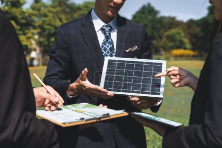 Téléchargez les photos : Réunion d'affaires en plein air sur l'énergie solaire, groupe de gens d'affaires travaillant et brainstorming sur l'utilisation des technologies d'énergie alternative comme engagement de l'entreprise à l'effort de RSE. Pneumatique - en image libre de droit