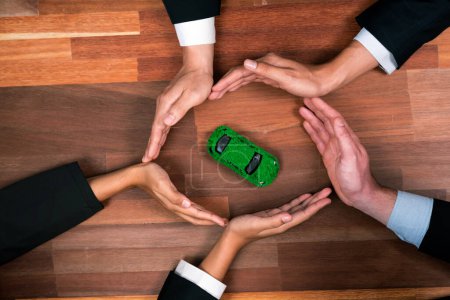 Photo for Top view business people holding EV car model as business synergy partnership unite and take action to utilized eco-transportation to reduce CO2 emission for sustainable and greener future. Quaint - Royalty Free Image