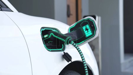 Photo for EV charger from home charging station plugged in and recharging electric car displaying digital battery status hologram. Smart and futuristic home energy infrastructure. Peruse - Royalty Free Image