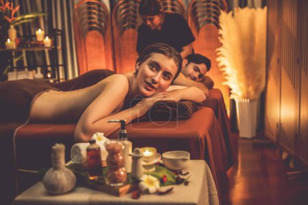 Photo for Couple customer having exfoliation treatment in luxury spa salon with warmth candle light ambient. Salt scrub beauty treatment in Health spa body scrub. Quiescent - Royalty Free Image