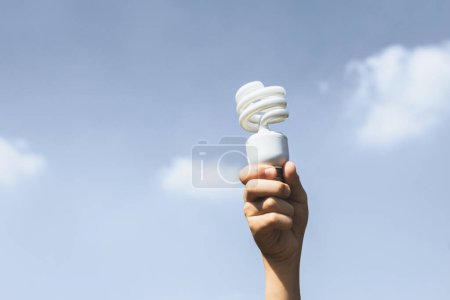 Photo for Recyclable electric waste held in hand up on sky background. Hand holding light bulb for recycle reduce and reuse concept to promote clean environment with recycling management. Gyre - Royalty Free Image