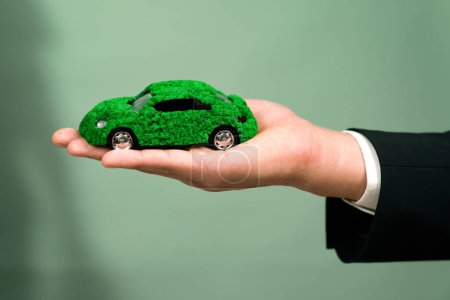 Téléchargez les photos : Homme d'affaires tenant éco modèle de voiture verte. Véhicule électrique utilisé par les entreprises respectueuses de l'environnement pour le transport écologique. Entreprise responsable avec zéro émission de CO2. Charmante. - en image libre de droit