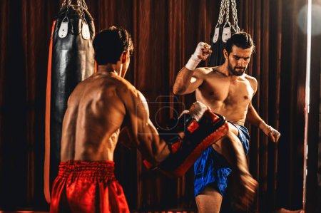 Téléchargez les photos : Le boxeur asiatique et caucasien Muay Thai déclenche une attaque de coups de pied dans une séance d'entraînement de boxe féroce, donnant un coup de pied à l'entraîneur sparring, mettant en valeur la technique et les compétences de boxe Muay Thai. Impulsion - en image libre de droit