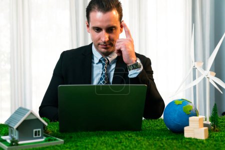 Téléchargez les photos : Un homme d'affaires planifie sur son ordinateur portable la mise en œuvre d'une énergie propre et durable pour réduire les émissions de CO2 dans une entreprise éco-verte et pour une Terre plus verte et durable. Charmante. - en image libre de droit
