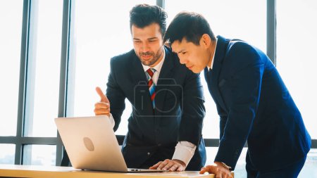 Photo for Two business people talk project strategy at office meeting room. Businessman discuss project planning with colleague at modern workplace while having conversation and advice on financial report. Jivy - Royalty Free Image
