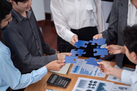 Photo for Corporate officer worker collaborate in office, connecting puzzle pieces with report paper on table as partnership and teamwork. Unity and synergy in business concept by merging jigsaw puzzle. Concord - Royalty Free Image