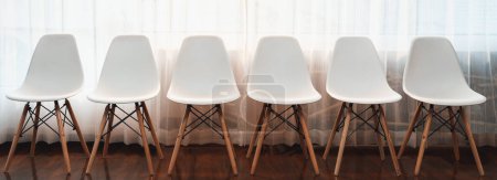 Photo for Panoramic shot of empty line of modern office chair at waiting room for job interview in corporate company. Indoor office furniture with minimal design front view white chair in corridor. Trailblazing - Royalty Free Image