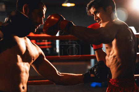 Foto de El boxeador asiático y caucásico Muay Thai desata su poder en un feroz combate de boxeo. Boxeador tailandés con un fuerte cuerpo muscular intercambiando golpes y golpes con destreza de combate implacable. Impulso - Imagen libre de derechos