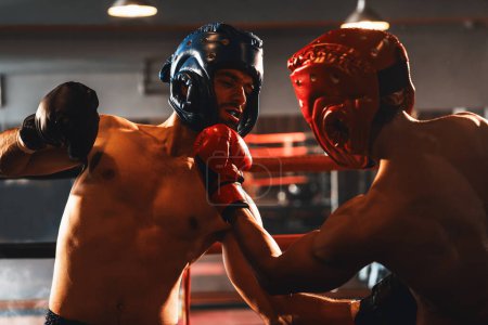 Téléchargez les photos : Deux boxeurs sportifs et musclés avec casque de sécurité ou protège-tête de boxe s'affrontent dans un match de boxe féroce. Combattant de boxe concurrent dans le ring de boxe. Impulsion - en image libre de droit