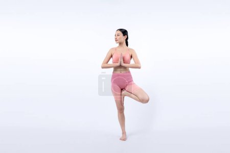 Photo for Asian woman in sportswear doing yoga exercise in standing pose on fitness as her workout training routine. Healthy body care and meditation yoga lifestyle in full shot on isolated background. Vigorous - Royalty Free Image