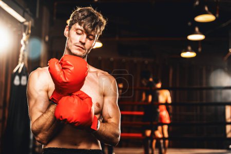Téléchargez les photos : Combattant de boxe pose torse nu, boxeur homme caucasien portant un gant rouge en position de garde défensive prêt à se battre et frapper à la salle de gym avec anneau et équipement de boxe en arrière-plan. Impulsion - en image libre de droit