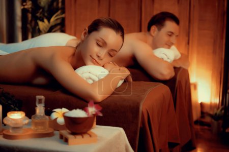 Foto de Cliente de pareja caucásica que disfruta de un relajante masaje de spa anti-estrés y mimos con belleza recreación de la piel de ocio en el cálido spa de salón de iluminación de velas en un resort de lujo u hotel. Silencioso. - Imagen libre de derechos