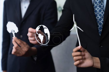 Téléchargez les photos : Groupe de gens d'affaires détenant une icône alternative nette zéro énergie pour une Terre plus verte et durable avec une technologie d'énergie renouvelable pour réduire les émissions de CO2. Charmante. - en image libre de droit