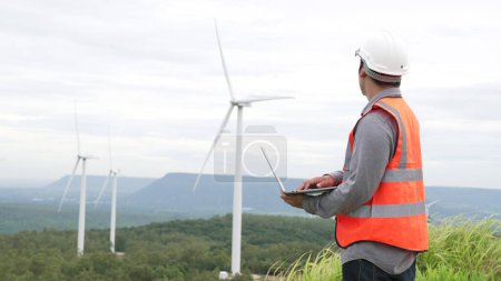 Téléchargez les photos : Ingénieur travaillant sur un parc éolien au sommet d'une colline ou d'une montagne en milieu rural. Idéal progressif pour la production future d'énergie renouvelable et durable. Production d'énergie à partir d'éoliennes. - en image libre de droit