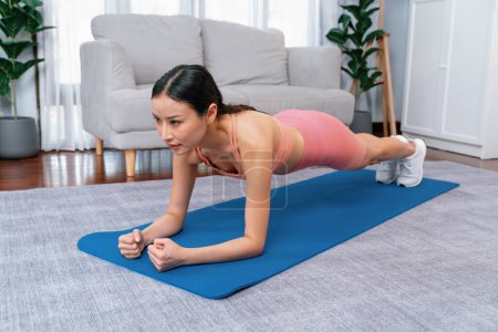 Foto de Ajuste joven mujer asiática cepillando en el piso de la sala de estar. Rutina de entrenamiento de estilo de vida saludable en casa. Equilibrio y resistencia ejerciendo el concepto. Vigoroso - Imagen libre de derechos