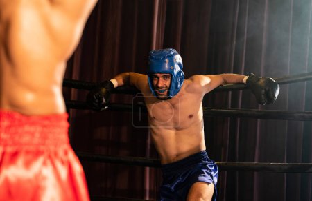 Foto de Boxeador luchador con casco de boxeo en una lucha feroz e intensa, mientras que el competidor luchando con la espalda contra el anillo que muestra resistencia y determinación. Impulso - Imagen libre de derechos