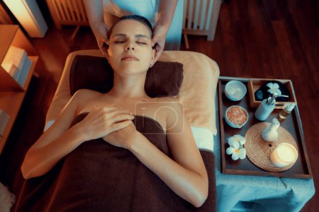 Photo for Caucasian woman enjoying relaxing anti-stress head massage and pampering facial beauty skin recreation leisure in warm candle lighting ambient salon spa in luxury resort or hotel. Quiescent - Royalty Free Image