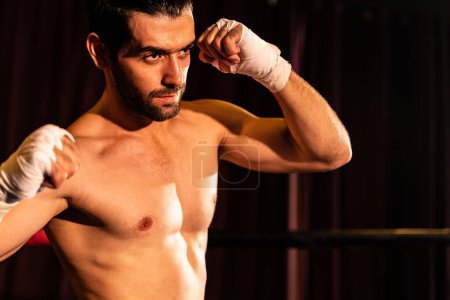 Photo for Boxing fighter shirtless posing, caucasian boxer punch his bare fist and wrap in front of camera, aggressive stance and ready to fight at the boxing ring. Impetus - Royalty Free Image