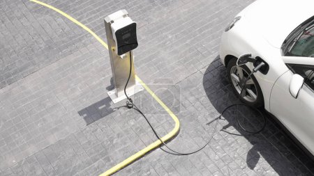 Foto de Innovación progresiva estación de carga urbana eléctrica en la calle con batería de vehículo eléctrico cargada con energía verde para la preocupación ambiental con el fin de reducir las emisiones de CO2. - Imagen libre de derechos