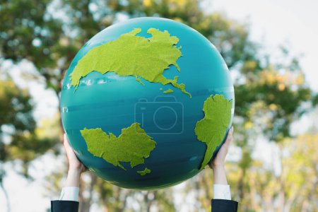 Téléchargez les photos : Concept de journée de la Terre avec grand globe terrestre tenu à la main dans le ciel pour promouvoir la sensibilisation à l'environnement afin de résoudre le réchauffement climatique avec la durabilité environnementale et le principe ESG. Pneumatique - en image libre de droit