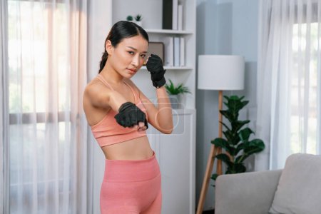 Foto de Ajuste joven mujer asiática retrato en ropa deportiva preparándose antes de la rutina de ejercicio saludable en casa. Entrenamiento de fitness doméstico en la sala de estar. Vigoroso - Imagen libre de derechos