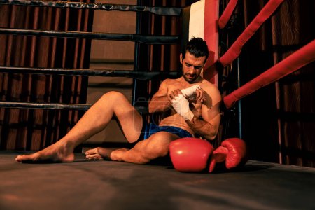 Photo for Caucasian boxer with pain and injury after intense boxing training or fighting match, sitting at the edge of ring. Physical injury in sport concept. Impetus - Royalty Free Image