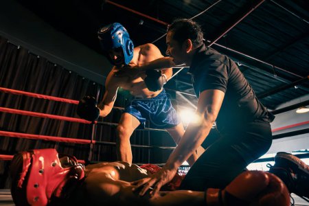 Photo for Boxing referee intervene, halting the fight to check fallen competitor after knock out. Intense and fierce boxing match with referee pauses the action for boxer fighters safety after KO. Impetus - Royalty Free Image