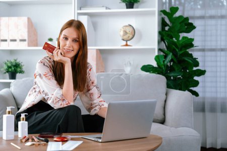 Téléchargez les photos : Jeune femme heureuse acheter des produits par des achats en ligne à la maison tout en commandant des articles sur Internet avec système de paiement en ligne par carte de crédit protégé par la plus haute cybersécurité de la plate-forme de boutique en ligne - en image libre de droit