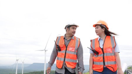 Foto de Ingenieros masculinos y femeninos trabajando en un parque eólico en lo alto de una colina o montaña en el campo. Ideales progresivos para la producción futura de energía renovable y sostenible. - Imagen libre de derechos