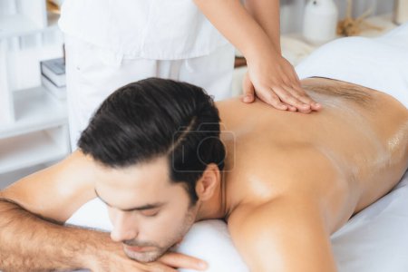 Photo for Caucasian man customer enjoying relaxing anti-stress spa massage and pampering with beauty skin recreation leisure in day light ambient salon spa at luxury resort or hotel. Quiescent - Royalty Free Image