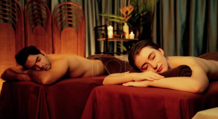 Photo for Caucasian couple customer enjoying relaxing anti-stress spa massage and pampering with beauty skin recreation leisure in warm candle lighting ambient salon spa at luxury resort or hotel. Quiescent - Royalty Free Image