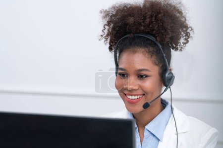 Téléchargez les photos : Femme d'affaires afro-américaine portant casque de travail dans le bureau pour soutenir client crucial à distance ou collègue. Le centre d'appels, le télémarketing, l'agent de soutien à la clientèle fournissent le service sur appel vidéo. - en image libre de droit