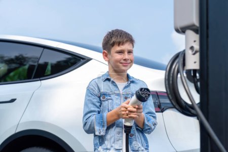 Photo for Little boy recharging eco-friendly electric car from EV charging station. EV car road trip travel concept for alternative transportation powered by clean renewable and sustainable energy. Perpetual - Royalty Free Image