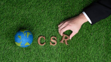 Photo for Hand arrange wooden alphabet text in CSR on biophilic background with Earth sign as eco symbol for corporate social responsible with net zero and environmental campaign for greener planet. Gyre - Royalty Free Image