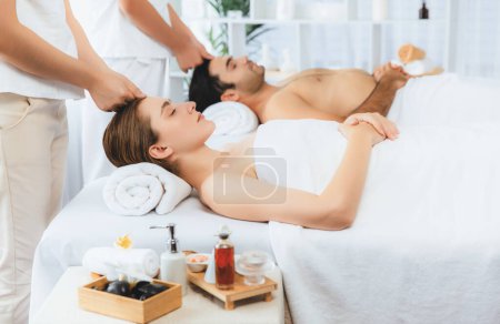 Téléchargez les photos : Couple caucasien profiter relaxant anti-stress massage de la tête et choyer beauté du visage loisirs de la peau dans dayspa lumière moderne ambiant au complexe de luxe ou un salon de spa de l'hôtel. Tranquillité - en image libre de droit