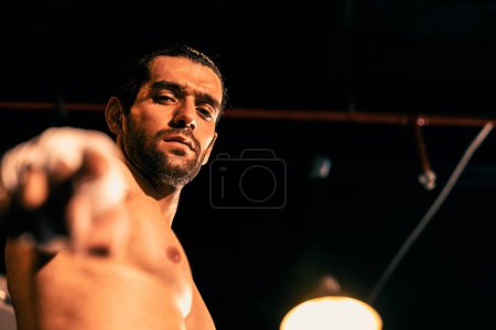 Photo for Boxing fighter shirtless posing, caucasian boxer punch his bare fist and wrap in front of camera, aggressive stance and ready to fight at the boxing ring. Impetus - Royalty Free Image