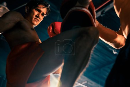 Photo for Asian and Caucasian Muay Thai boxer unleash knee attack in fierce boxing training session, delivering knee strike to sparring trainer, showcasing Muay Thai boxing technique and skill. Impetus - Royalty Free Image