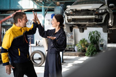 Photo for Two happy vehicle mechanic celebrate and high five after made successful car inspection or repair in automotive service car workshop. Technician team enjoy accomplishment together in garage. Oxus - Royalty Free Image