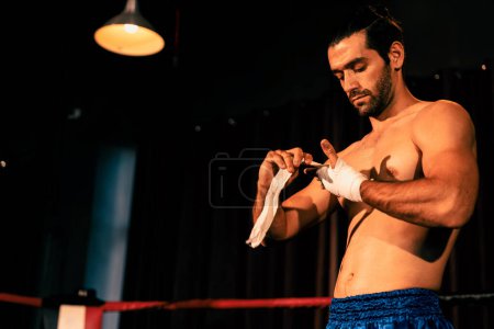 Téléchargez les photos : Portrait de boxeur caucasien avec corps musclé et athlétique enveloppant sa main ou son poing sur le ring avant le match ou l'entraînement de combat de boxe. Impulsion - en image libre de droit