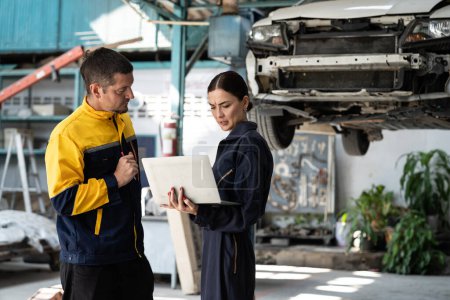 Photo for Two vehicle mechanic working together, conduct car inspection with laptop. Automotive service technician in uniform carefully make diagnostic troubleshooting to identify error. oxus - Royalty Free Image