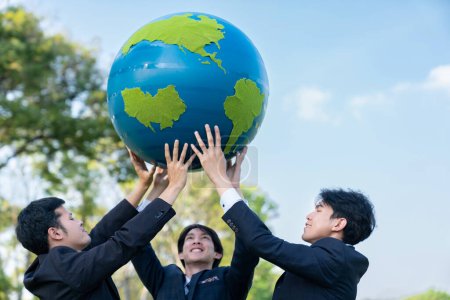 Téléchargez les photos : Concept de journée de la Terre avec grand globe terrestre tenu par un groupe de gens d'affaires asiatiques équipe promouvant la sensibilisation à l'environnement pour résoudre le réchauffement climatique avec la durabilité environnementale et le principe ESG. Pneumatique - en image libre de droit