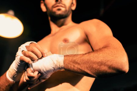 Foto de Retrato de boxeador caucásico con cuerpo musculoso y atlético envolviendo su mano o puño en el ring antes del combate de boxeo o entrenamiento. Impulso - Imagen libre de derechos