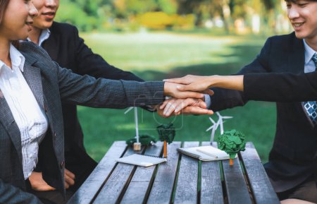 Photo for Business people join hand together as teamwork and unity, outdoor business meeting table. Eco-friendly practices and collaboration in corporate social responsibility for greener environment. Gyre - Royalty Free Image