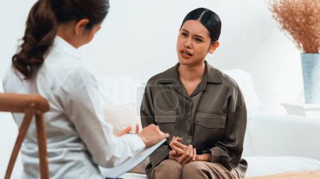 Photo for Sad PTSD woman patient in uttermost therapy for mental health with psychologist, depression or grief after life failure. Frustrated trauma young woman talking to a psychologist about emotion in office - Royalty Free Image