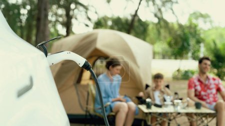 Photo for Outdoor adventure and family vacation camping in nature travel by eco friendly car for sustainable future. Lovely sit on trunk, charging EV car with EV charging station in campsite. Panorama Perpetual - Royalty Free Image