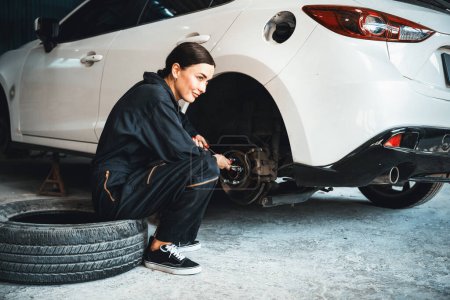 Photo for Hardworking female mechanic changing car wheel in auto repair workshop. Automotive service worker changing leaking rubber tire in concept of professional car care and maintenance. Oxus - Royalty Free Image