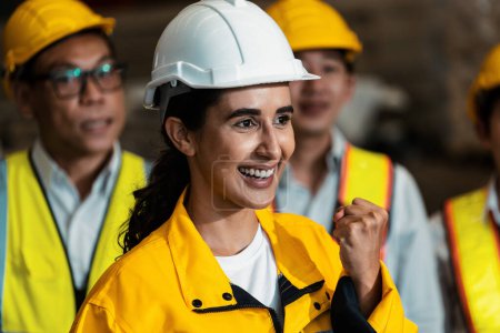 Photo for Smiling and happy, confident female engineer woman proudly clench her fist in workplace of heavy industry factory, standing alongside diverse coworker in harmonious portrait of unity. Exemplifying - Royalty Free Image
